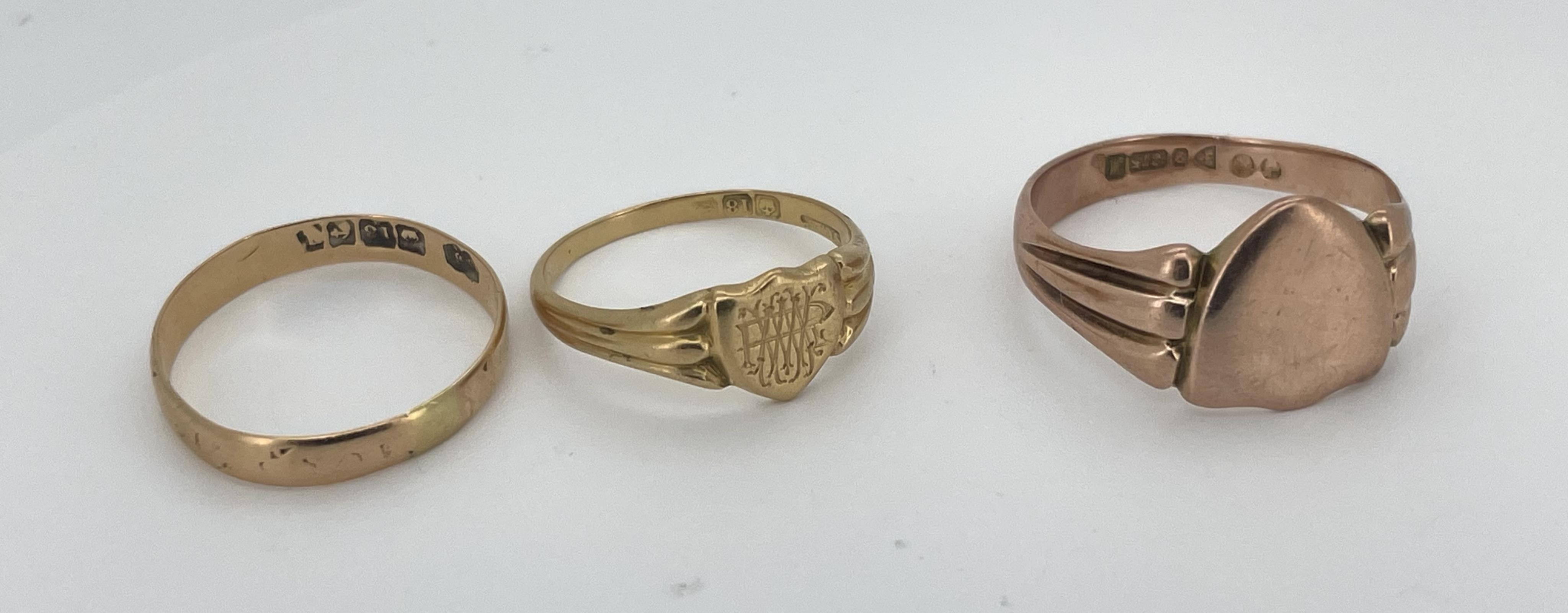 Three gold rings, comprising: a Victorian 18ct gold shield-shaped signet ring, bearing the monogram RMW, to a fluted band, size O, British hallmarks, gross weight approximately 3 grams; an 18ct gold wedding band, size R,